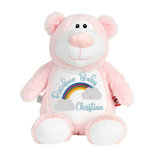 A pink plush teddy bear with a white belly patch that reads 'Rainbow Baby Christian' with a small rainbow and clouds, shown on a plain white background.